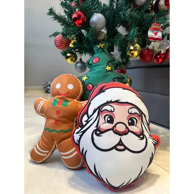 Almofadas recortadas em forma de rosto de Papai Noel, boneco de gengibre e árvore verde, apoiadas no chão sob a árvore