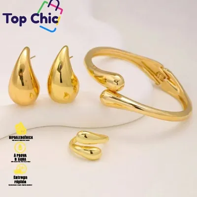 Bracelete dourado com duas pontas em gota que se cruzam, ao lado de brincos e anel em gota no mesmo estilo