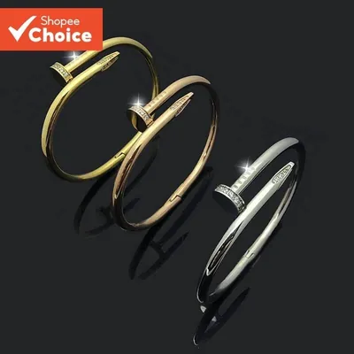 Três braceletes em formato de prego, dourado, rosé e prateado, com pedrinhas brilhantes, sobre fundo preto espelhado