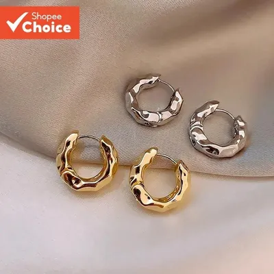 Dois pares de brincos argola grossos com textura ondulada, um dourado e um prateado, sobre tecido acetinado bege