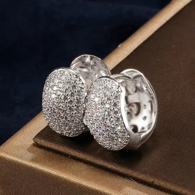 Par de brincos argola largos totalmente cravejados de zircônias, prateados, sobre caixa marrom