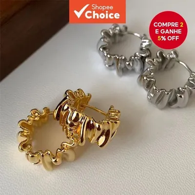 Dois pares de brincos argola com textura ondulada e franzida, um dourado e um prateado, sobre superfície branca