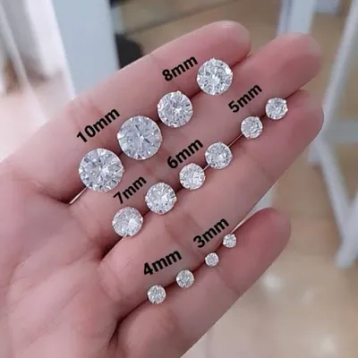 Mão aberta com pares de brincos ponto de luz de zircônia lado a lado, marcados de 3 mm a 10 mm