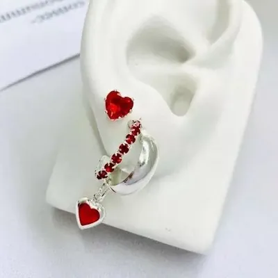 Trio de brincos em orelha de vitrine: coração vermelho, argola com pedras vermelhas e argolinha prateada com coração