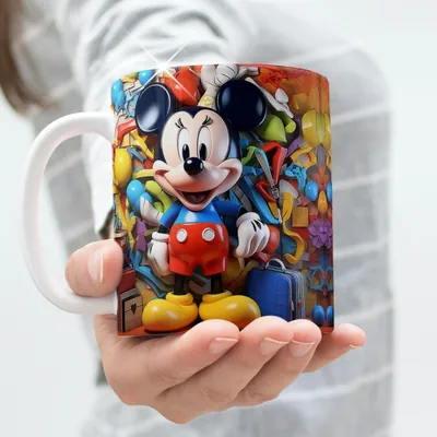 Mão segurando caneca com alça branca e estampa colorida do Mickey sorrindo entre balões, fitas e uma mala azul