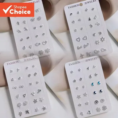 Quatro cartelas brancas com doze pares de brincos pequenos prateados: estrelas, luas, corações, folhas e flocos de neve