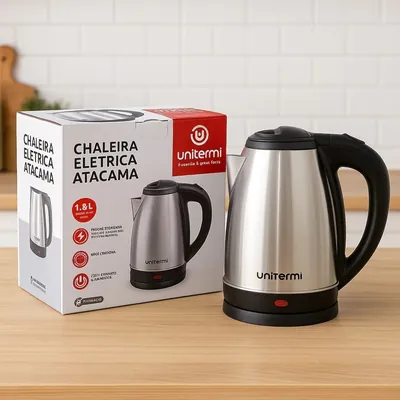 Chaleira elétrica de inox escovado com tampa, alça e base pretas ao lado da caixa branca e vermelha sobre bancada de madeira