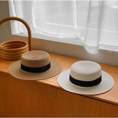 Dois chapéus de copa reta e aba média, um bege natural e um off-white, com faixa preta, sobre balcão de madeira