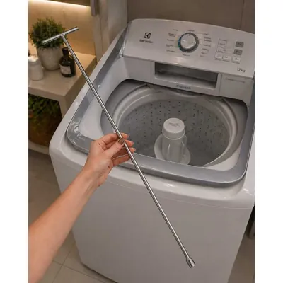 Mão segurando uma chave T metálica longa e fina sobre uma máquina de lavar de abertura superior com agitador no centro