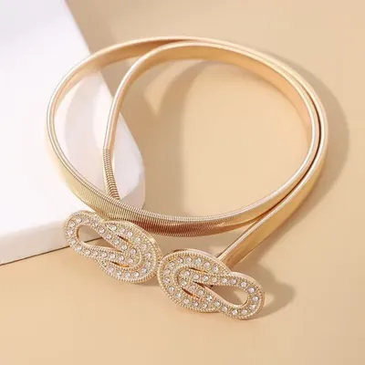 Cinto feminino de metal dourado em malha elástica enrolado, com fivela de dois laços entrelaçados cravejados de strass