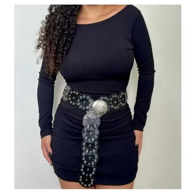 Mulher de vestido preto canelado usando cinto de discos pretos com ilhoses prateados e medalhão central no quadril