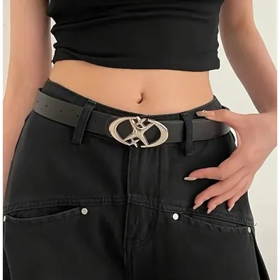 Cinto preto com fivela oval prateada em forma de estrela sobre calça jeans preta larga e cropped preto