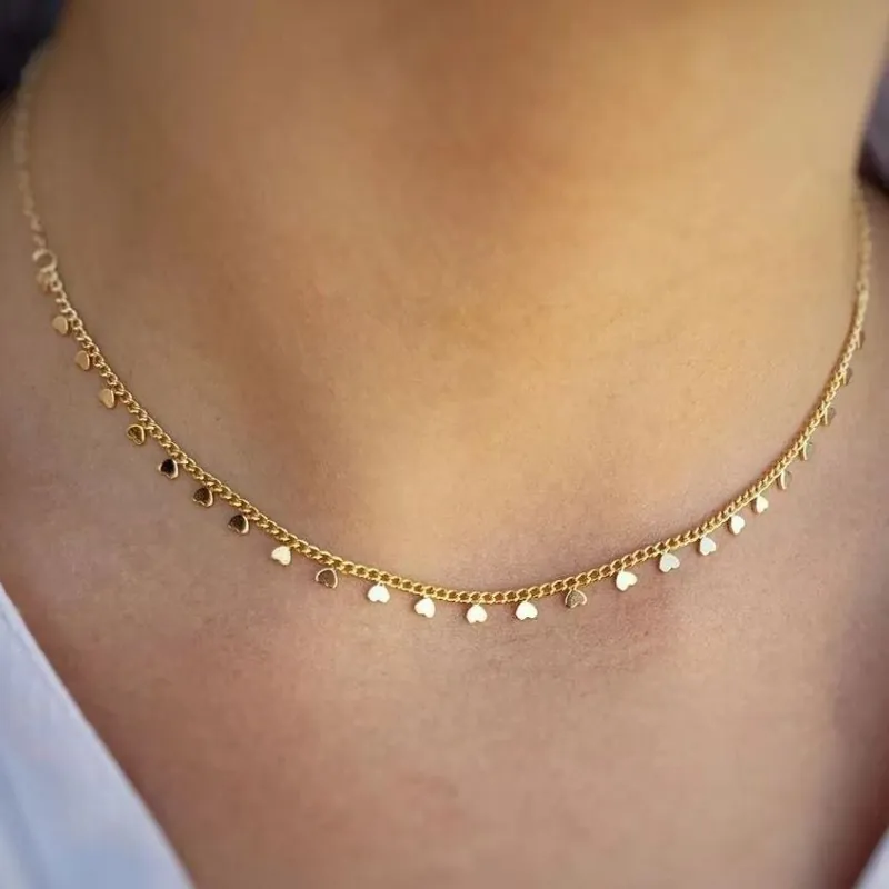 Colar choker dourado de corrente fina com vários mini corações lisos pendurados, usado rente ao pescoço