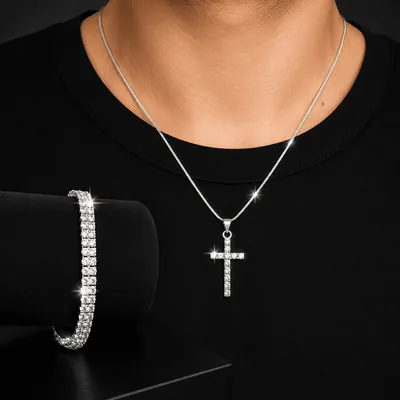Homem de camiseta preta usando corrente fina prateada com cruz cravejada; ao lado, pulseira de pedras em suporte preto