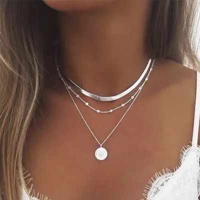 Colar prateado de três camadas no pescoço: corrente lisa e larga, fio com bolinhas e pingente redondo de sol