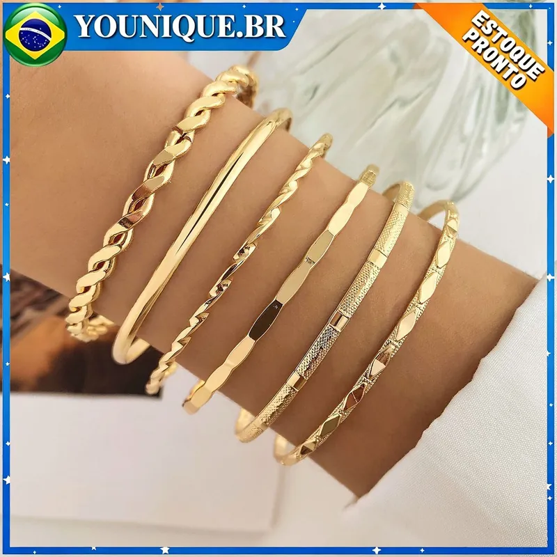 Pulso com seis braceletes dourados rígidos de texturas diferentes: torcidos, liso, facetado e granulado