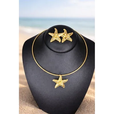 Choker dourado de aro fino com pingente de estrela-do-mar e par de brincos iguais em busto preto, com praia ao fundo