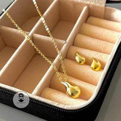Colar com pingente de gota dourada polida e par de brincos de gota em porta-joias de veludo bege