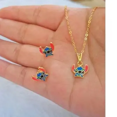 Colar de corrente dourada e par de brincos com o rosto do Stitch em esmalte azul e vermelho, apoiados na palma de uma mão