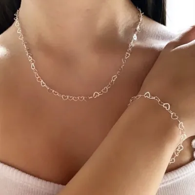 Mulher usando colar e pulseira prateados feitos de pequenos corações vazados ligados em corrente