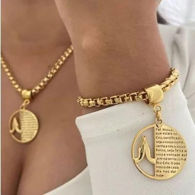 Colar e pulseira dourados de corrente grossa com medalha redonda de mãos em oração e texto do Pai Nosso