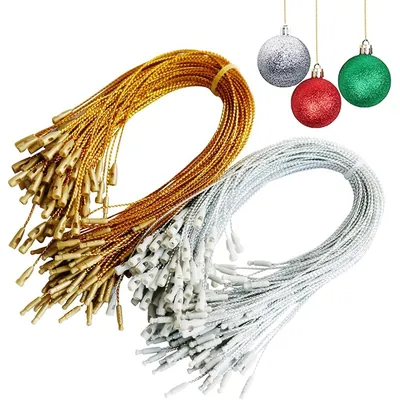 Dois maços de cordões torcidos, um dourado e um prateado, com travas plásticas nas pontas e três bolas de Natal ao lado