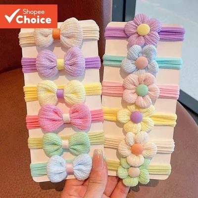 Duas cartelas de elásticos infantis em tons pastel, uma com laços franzidos e outra com flores de miolo redondo