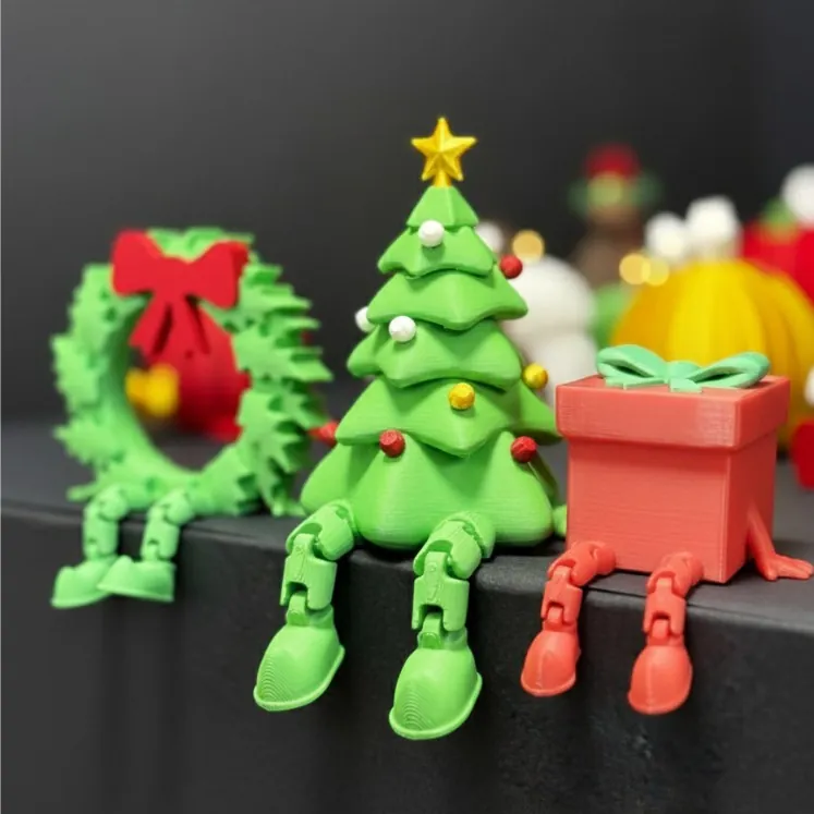 Árvore de Natal, guirlanda e caixa de presente em plástico com pernas articuladas sentadas na beira de prateleira preta