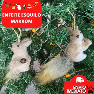 Dois enfeites de esquilo bege com pinhas nas patas e rabo felpudo pendurados por cordão em árvore de Natal com luzes