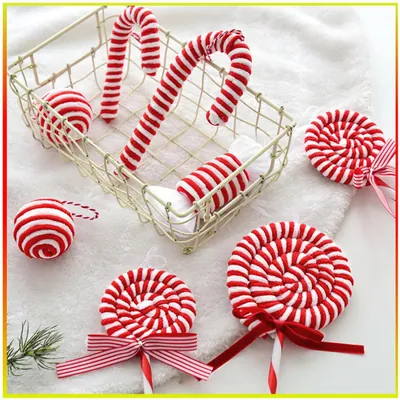 Enfeites listrados vermelho e branco em forma de bengalas, pirulitos com laço, bolas e bala, numa cesta de arame