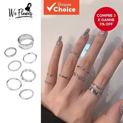 Sete anéis prateados ao lado de uma mão com unhas cromadas usando os aros empilhados e acima da articulação