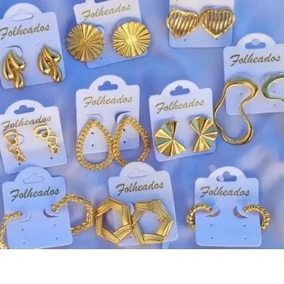 Dez pares de brincos dourados em cartelas brancas escritas Folheados, com argolas, corações, gotas e formas geométricas