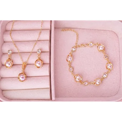 Colar, brincos e pulseira dourados com pérolas rosadas e pedrinhas claras em porta-joias de veludo rosa