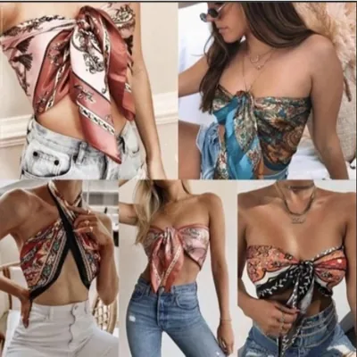 Cinco mulheres usando lenços de cetim estampados em rosa, azul e coral amarrados como top cropped com jeans