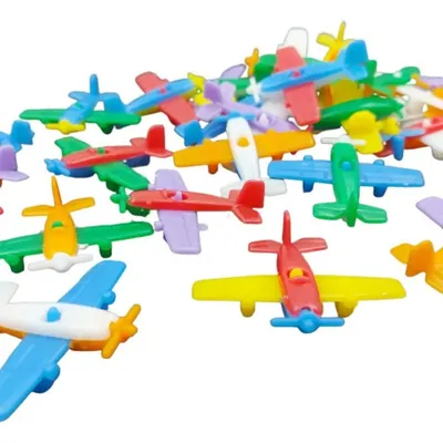 Vários mini aviões de plástico coloridos, com asas, hélices e cauda em cores diferentes, espalhados sobre fundo branco