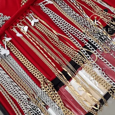 Mostruário vermelho com dezenas de correntes e pulseiras douradas e prateadas penduradas, de elos variados