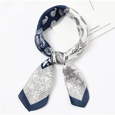 Lenço quadrado acetinado com estampa paisley, metade azul-marinho e metade branca, amarrado em nó com pontas cinza