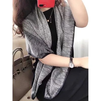 Mulher de roupa preta com lenço quadrado cinza e preto de traços finos sobre os ombros, tirando foto com celular vermelho