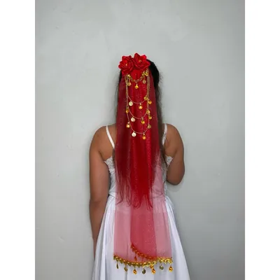 Mulher de costas com vestido branco e lenço vermelho translúcido no cabelo, rosas vermelhas e correntes de moedas douradas