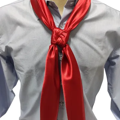 Lenço gaúcho vermelho liso e brilhante amarrado com nó trançado sobre camisa azul-clara de manga longa