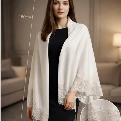 Mulher de vestido preto com pashmina off-white sobre os ombros, barrado de renda nas pontas e detalhe ampliado das pérolas