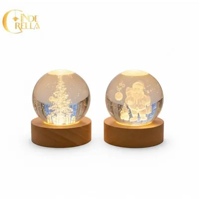 Duas esferas transparentes com árvore de Natal e Papai Noel gravados por dentro, acesas sobre bases de madeira clara