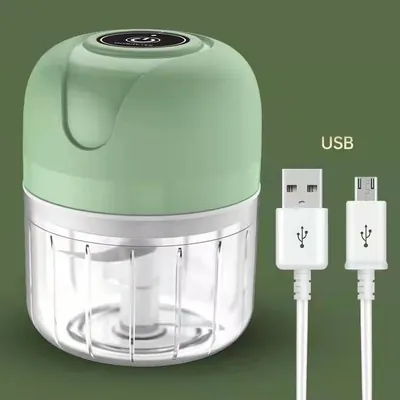 Mini processador com tampa verde-menta, botão preto no topo, copo transparente e cabo USB branco ao lado, fundo verde