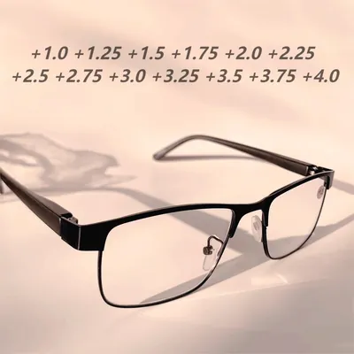 Óculos de leitura com armação preta de metal e lentes retangulares sobre fundo bege com sombra de folhas