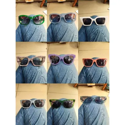 Nove óculos de sol de armação grossa verde, lilás, branca, rosa e cinza apoiados num joelho de calça jeans
