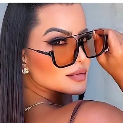 Mulher de cabelo escuro preso segurando óculos de sol quadrados grandes de meia armação com lentes cor champanhe