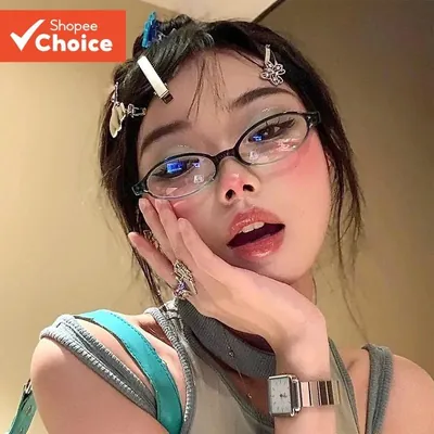 Jovem com presilhas prateadas no cabelo usando óculos ovais pequenos de armação escura e lentes claras, mão no rosto