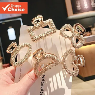 Cinco piranhas de cabelo douradas com strass: retângulo, laço, oval, meia-lua e coração, presas num cartão