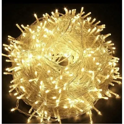 Rolo de cordão de luzes de LED em tom amarelado quente, com fio transparente, aceso sobre fundo preto