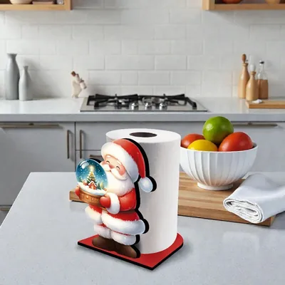 Suporte de papel toalha com figura de Papai Noel segurando globo de neve, sobre base vermelha numa bancada de cozinha